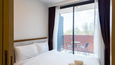 a bedroom with a bed and a window with a table at Апартаменты в Лагуне SkyPark c видом на гольф поле in Bang Tao Beach