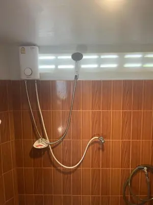 a shower in a bathroom with a hose on the wall at Pyramid Bangalow in Ban Laem Sai