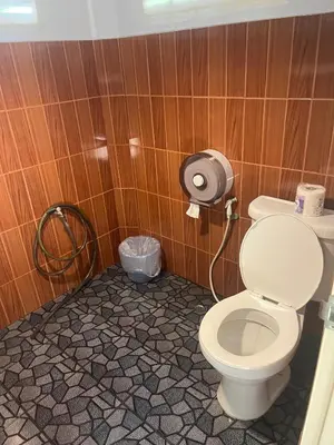 a bathroom with a toilet in a wooden wall at Pyramid Bangalow in Ban Laem Sai