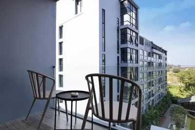 two chairs and a table on a balcony with a building at Tropics Kamala Pool View Studio CTG B608 in Kamala Beach
