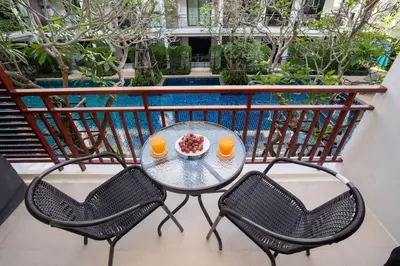 a table with two chairs and two cups of orange juice at The Title Rawai West Wing Pool View Suite in Rawai Beach