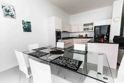 a kitchen with a glass table and white chairs at Large Penthouse 3BR with jacuzzi, Best for Kids in Karon Beach