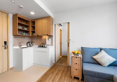 a living room with a blue couch and a kitchen at Laguna Skypark by My Home Phuket in Bang Tao Beach