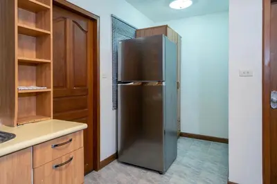 a stainless steel refrigerator in a kitchen with wooden cabinets at Solene Home Patong in Patong Beach