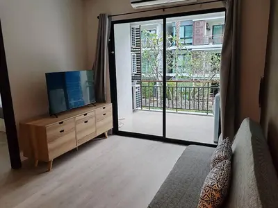 a living room with a tv and a sliding glass door at The Title Rawai Beach front 2BD in Rawai Beach