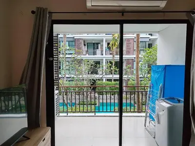 a door to a balcony with a view of a building at The Title Rawai Beach front 2BD in Rawai Beach