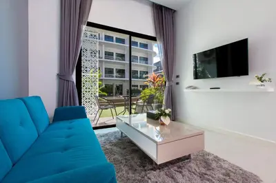 a living room with a blue couch and a large window at Utopia Naiharn in Nai Harn Beach