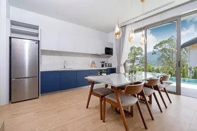a kitchen with blue cabinets and a table and chairs at Himmapana Villas - Hills in Kamala Beach