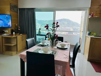a dining room table with a vase of flowers on it at Patong Tower Superior Apt 2 bedrooms 2 bathrooms in Patong Beach