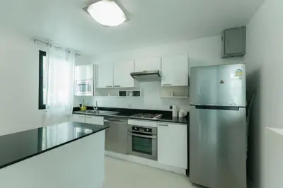 a kitchen with white cabinets and a stainless steel refrigerator at Kamala family friendly pool villa by Lofty in Kamala Beach