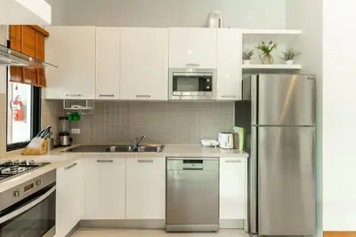 a kitchen with white cabinets and a stainless steel refrigerator at Tanode Villa 511 by Villacarte in Bang Tao Beach