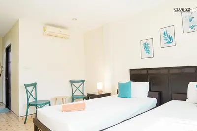 two beds in a room with two chairs at Club22 Kamala Suites, Kamala Beach in Kamala Beach