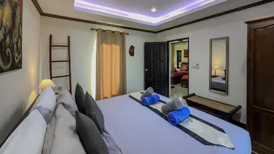 a bedroom with a large white bed with blue pillows at Garden bungalows 4br with private pool in Rawai Beach