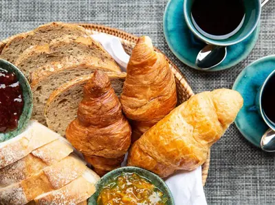 a basket of bread and croissants and a cup of coffee at Infinity View by Elite Havens in Kata Beach