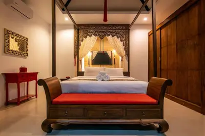 a bedroom with a large bed with a red bench at Oriental 3br private Pool Villa in Rawai Beach