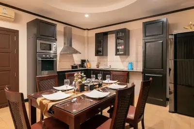 a kitchen with a wooden table with chairs and a kitchen with black appliances at Villa Rodentia 3br pool Villa in Rawai Beach