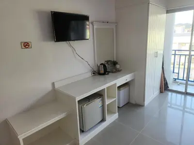 a room with a desk with a television on the wall at Santi White House Patong in Patong Beach