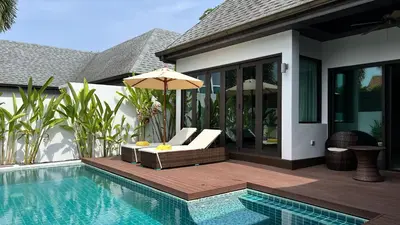 a patio with a chair and an umbrella next to a pool at Plunge Tropic Pool Villa near Nai Harn Beach in Rawai Beach