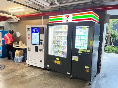 a man standing next to a drink vending machine at The Base Central - Luxury Resort-Style Comfort in Ban Rangeng